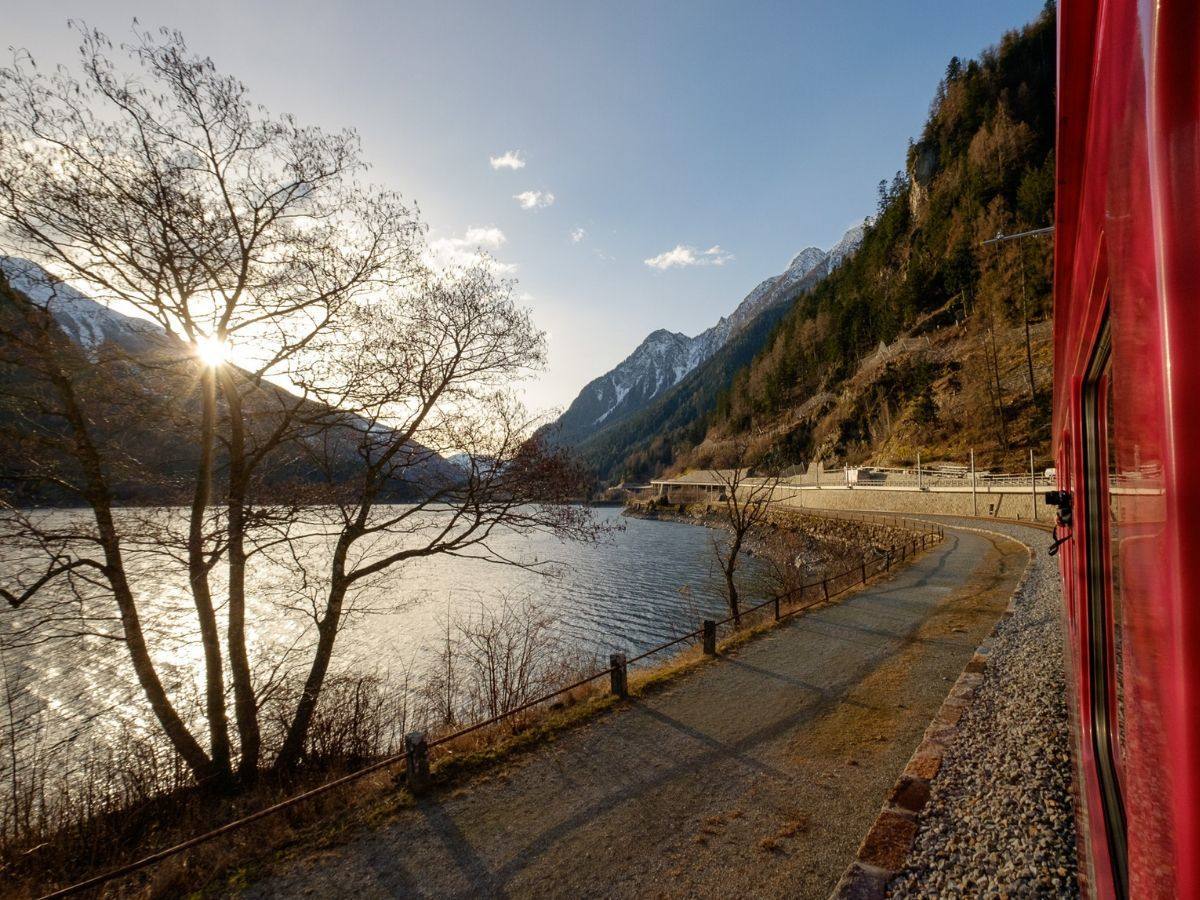 il trenino del Bernina costeggia il lago di Poschiavo all' alba il trenino del Bernina costeggia il lago di Poschiavo all' alba